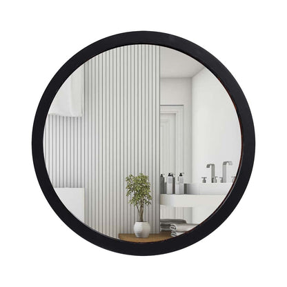 Round black-framed mirror reflecting a bathroom interior with a plant and sink.
