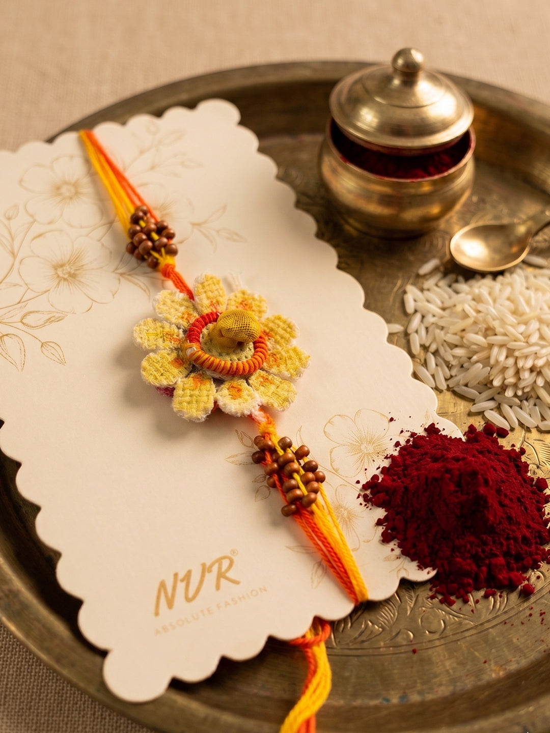 NVR Yellow Floral Seed Thread Rakhi with Roli Chawal Chandan Mishri
